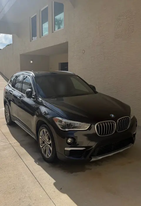 Black BMW X1 parked beside a building after an exterior detail