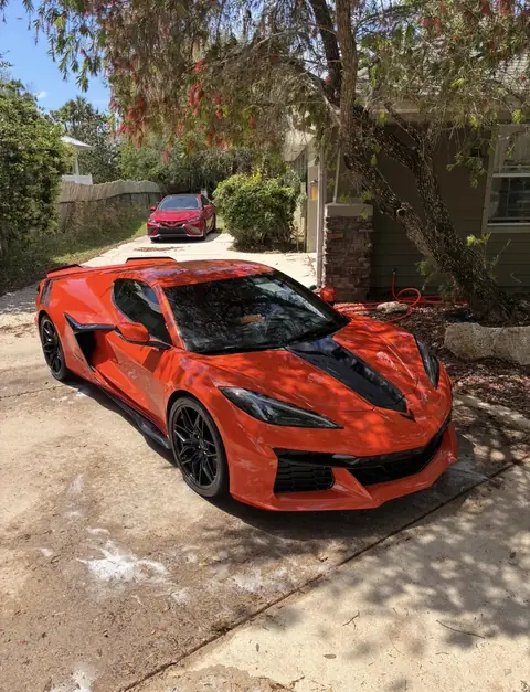 Orange Corvette C8 parked in a shaded driveway after an exterior detail