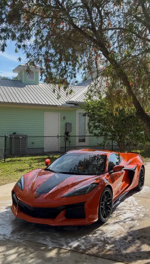 Orange Corvette C8 in a customer's driveway during a foam hand wash