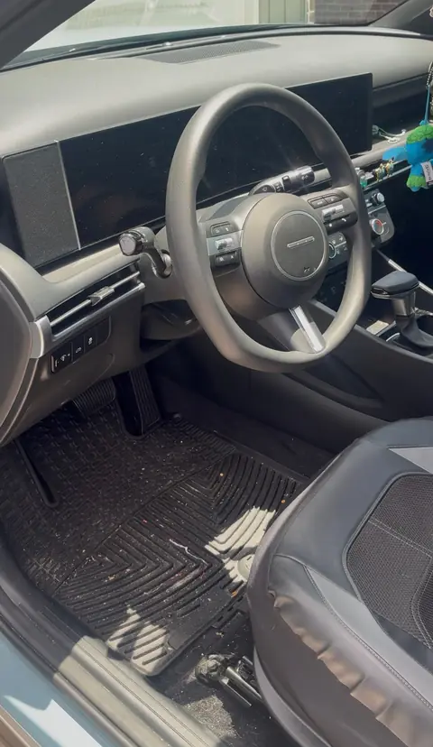 Hyundai sedan driver's area before an interior detail, with crumbs and debris on the rubber floor mat