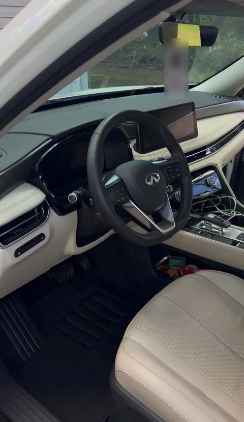 The same Infiniti SUV interior after detailing, with clean black floor mats and cream leather seat