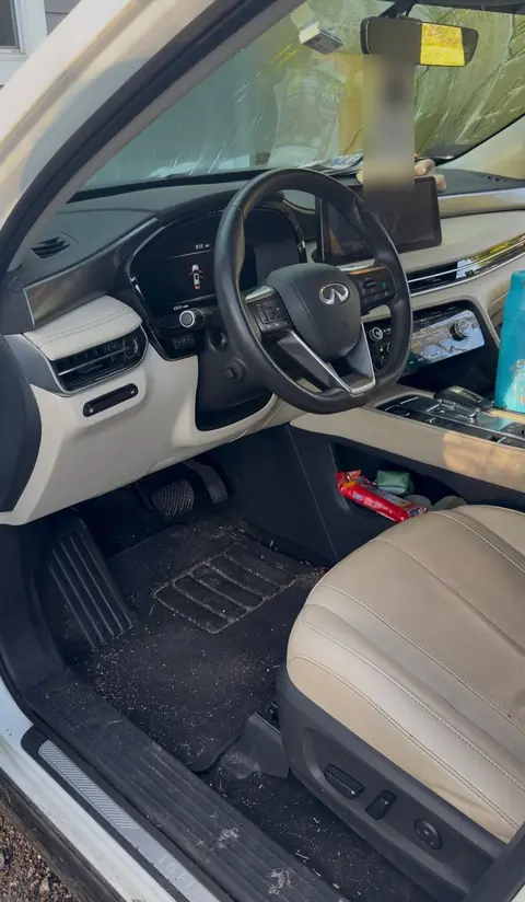 Infiniti SUV front interior before detailing, with dirt ground into the floor mats and clutter in the console