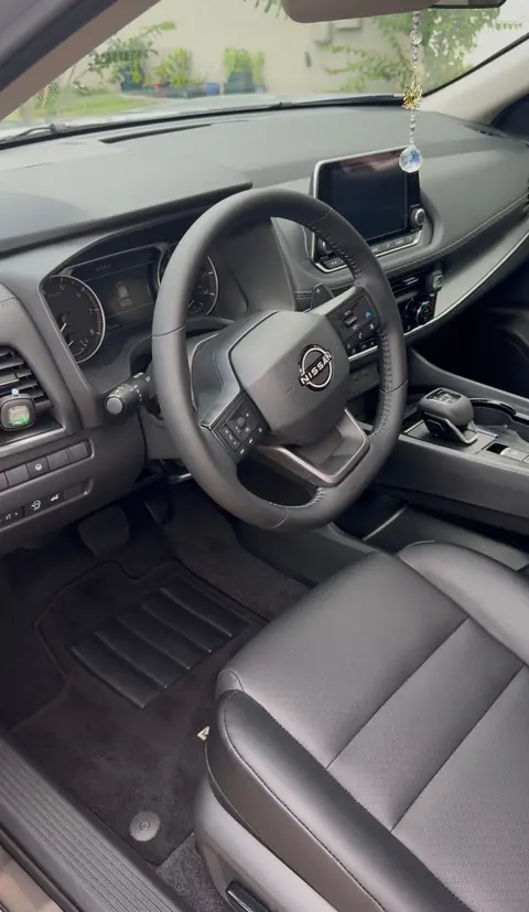 The same Nissan driver's area after an interior detail, with a clean floor mat, dash and seat
